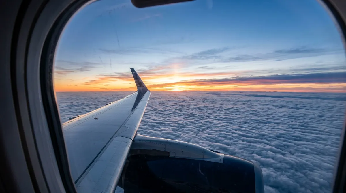 A sunrise over a sea of clouds seen from an airplane window